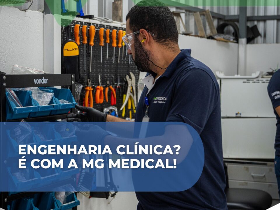 A imagem mostra um profissional técnico da área de engenharia clínica trabalhando em uma bancada organizada com ferramentas de manutenção. Ele utiliza equipamentos de proteção, como óculos de segurança e luvas, enquanto manipula peças e componentes técnicos armazenados em gavetas azuis. Ao fundo, há um painel com diversas ferramentas penduradas, como chaves de fenda e alicates, indicando um ambiente de manutenção especializado em equipamentos médicos. O profissional veste uma camisa com o logotipo da MG Medical Soluções Hospitalares. Sobre a imagem aparece um destaque gráfico com o texto: “Engenharia Clínica? É com a MG Medical!”, além do endereço do site da empresa. A cena transmite a ideia de assistência técnica especializada, organização e suporte profissional em engenharia clínica para hospitais e clínicas.